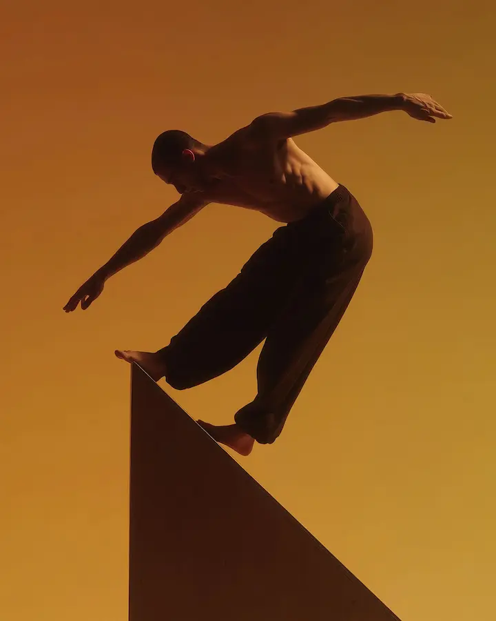A shirtless man balancing on the top of a structure in 16-9